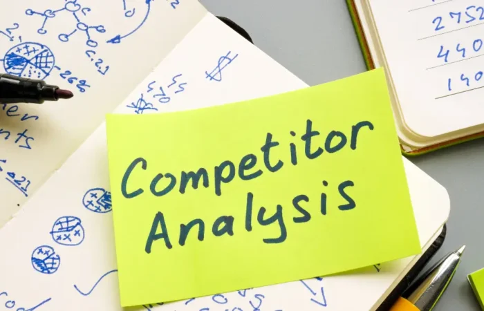 a yellow sticky note sat on a notebook with text saying competitor analysis