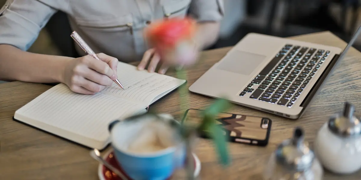 a picture of a person writing in a notebook to plan thier content curation