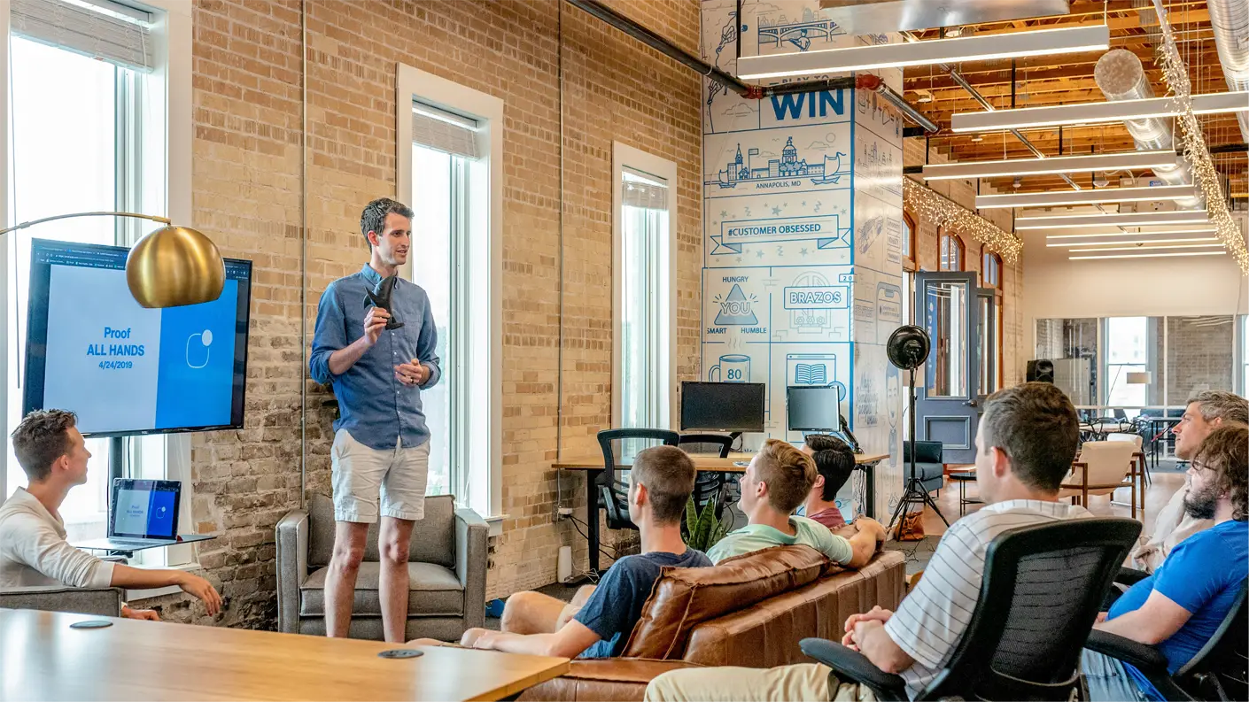 a man giving a presentation to a group of people in an modern office setting