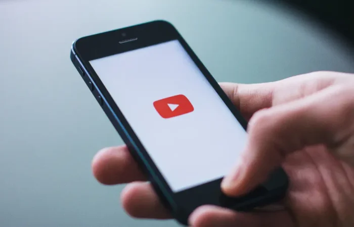 A person holding a phone that shows the YouTube logo