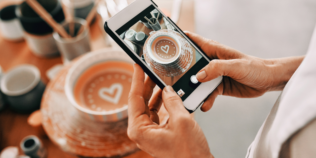 A photo of a smart phone showing a person taking a picture of a bowl, in which is a painted heart