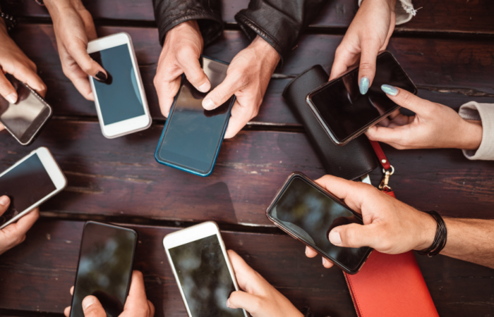 a group of people using phones against a dark wood table