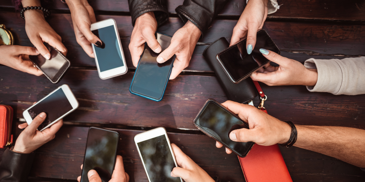 a group of people using phones against a dark wood table